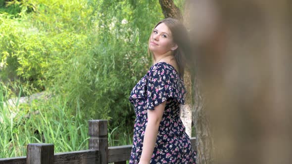 Back View of Beautiful Young Woman in Dress in Summer City Park