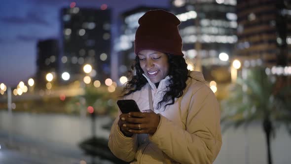 The Girl with Her Face Illuminated By the Light of the Mobile Phone Screen is Using the Smart Phone