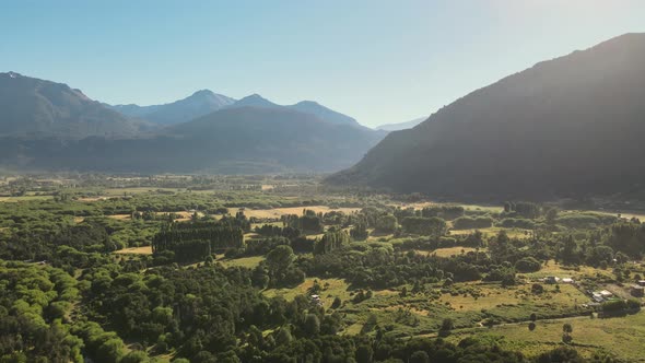 Pan left of El Hoyo valley flying over a beautiful woodland with mountains in background, Chubut, Pa