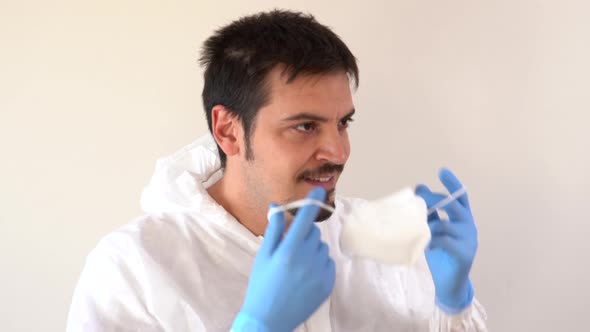 Doctor in PPE suit putting on a face mask in profile to the camera and looking when finished