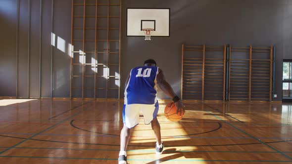 African american male basketball player practicing shooting with ball