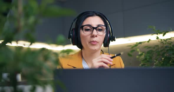Woman in Stylish Clothes in Headphones Sitting in front of Laptop During Online Webinar