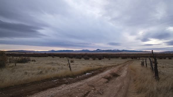 Looking down dirt road during timelapse as clouds move over field