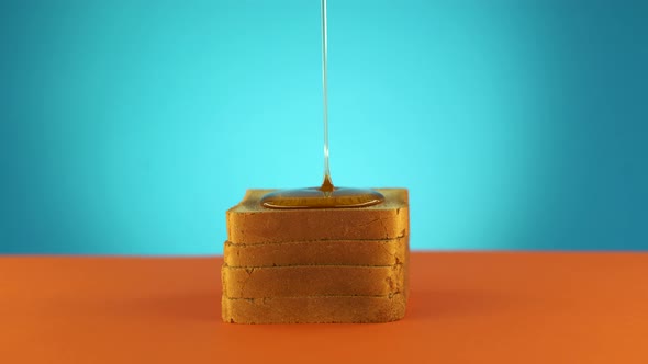 Liquid Honey Pouring on a Piece Bread