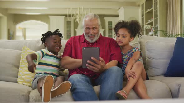 Grandfather and grandchildren using digital tablet at home