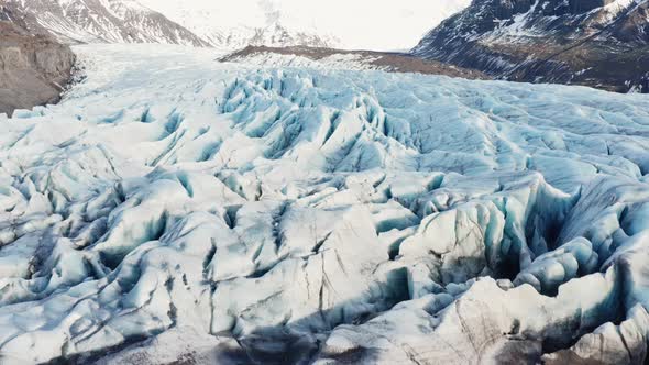 Drone Over Ice In Large Glacier At Foot Of Mountains