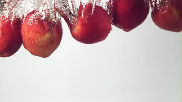 Super Slow Motion Red Apples Fall Under the Water with Air Bubbles