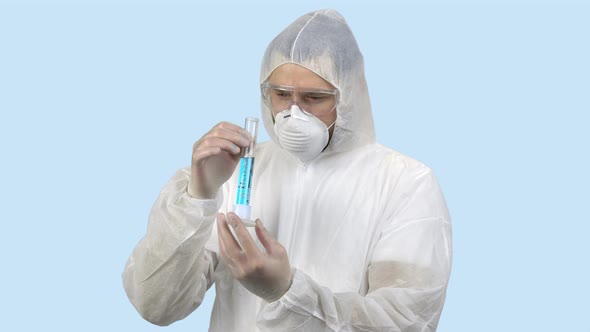 Medical Worker in Antiviral Protective Clothing Holding Test Tube with Blue Liquid