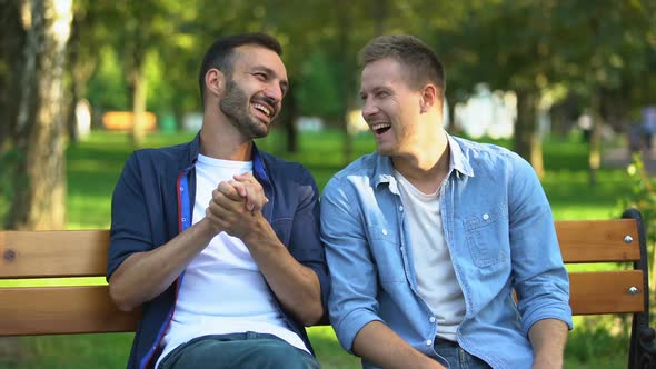 Male Friends Joking and Laughing on Bench at Park, Remembering Funny Stories