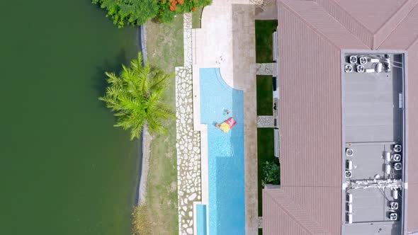 Aerial top-down descending over Punta Cana Lake Village summer holiday resort swimming pool with tou