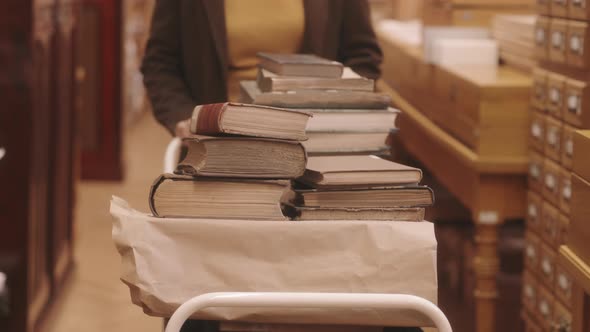 Librarian Carrying Old Books in Cart along Library