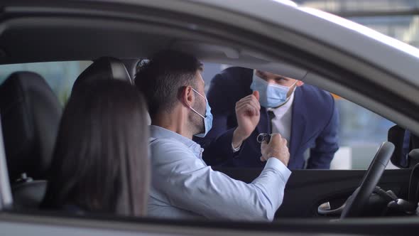 Masked Couple of Buyers Getting Key To Bought Auto