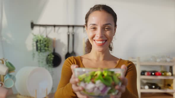 Portrait of Latino attractive woman hold salad bowl in kitchen at home.