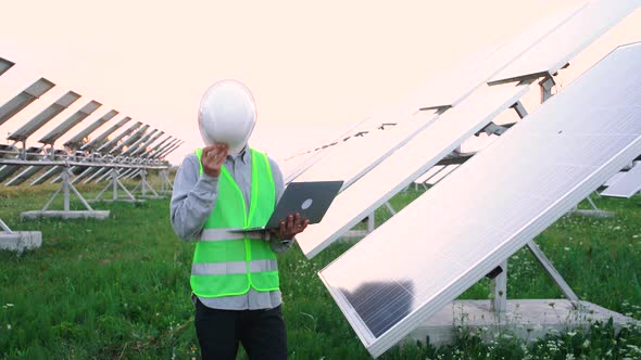 Happy Engineer, with Special Equipment, Holds a Laptop From Where He Controls the Productivity of