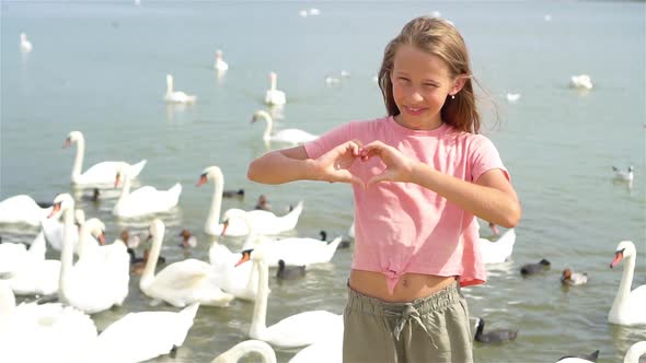 Little Girl Sitting on the Beach with Swans