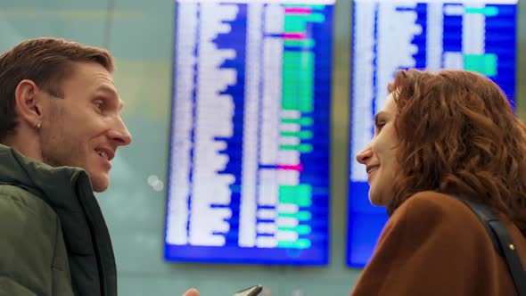 Young Couple Looking at Flight Schedule at Airport