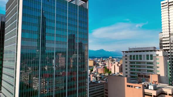 Aerial view of modern mirror skyscraper and 101 tower reflection in window during sunny day - Taipei