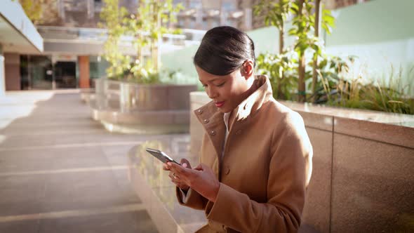 Mixed ethnicity business woman works on her cellphone