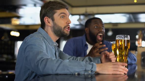 Smiling Male Supporters Clinking Beer Glasses in Pub, Celebrating Team Goal