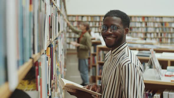 Portrait of Happy Afro Man by Book Shelves in Library