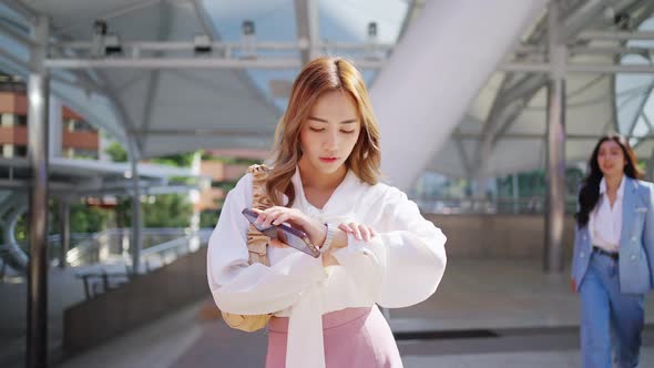 4K Asian business woman checking time on hand watch while walking in railway station in the morning.