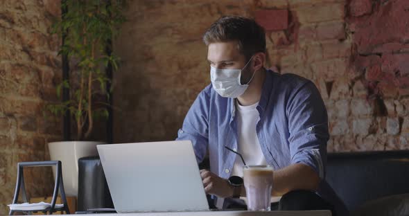 Young Businessman with Mask Using Laptop and Sitting It Coffee Shop