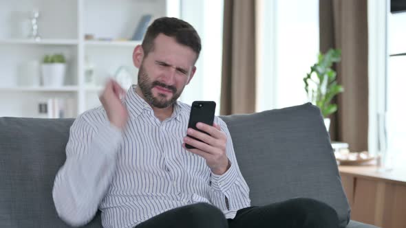 Upset Young Businessman Reacting To Loss on Smartphone at Home 