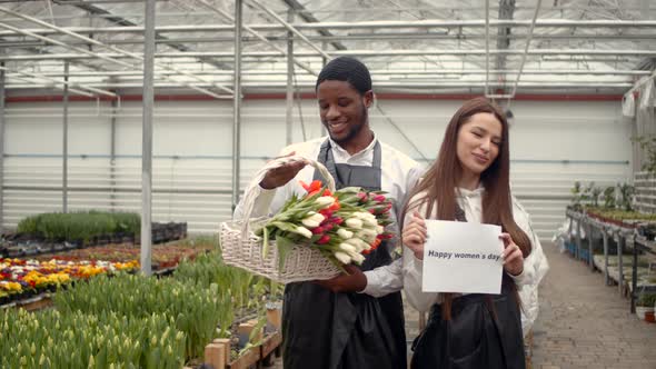 Woman Florist Holding Happy Women's Day Sheet of Paper at Greenhouse