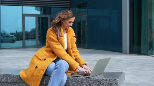 Business Woman Using Laptop Dressed Yellow Coat Sitting Outdoors Corporative Building Background