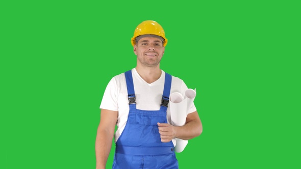 Construction worker walking with blue prints and smiling