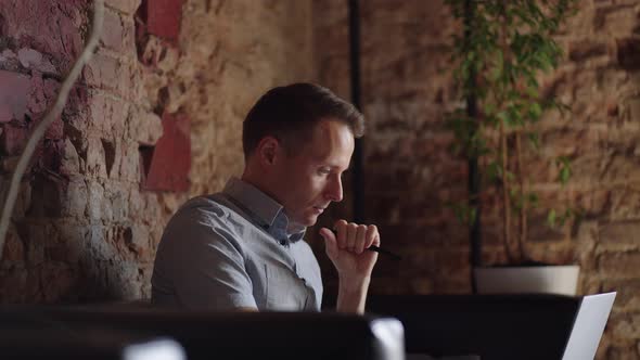 Thoughtful Serious Young Man Student Writer Sit at Home Office Desk with Laptop Thinking of