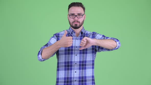 Confused Young Bearded Hipster Man Choosing Between Thumbs Up and Thumbs Down