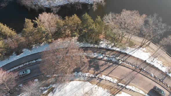 aerial footage of road by the lake shore during a sunny afternoon, cars going by