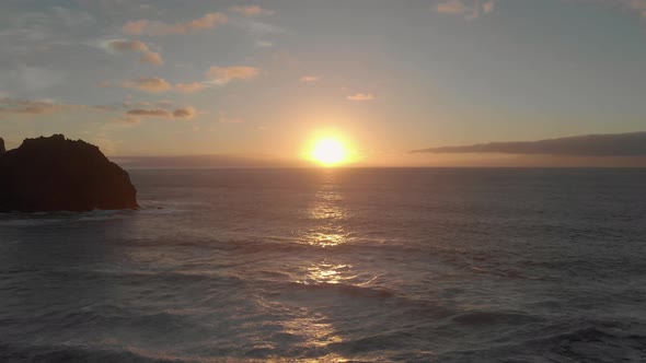 Sea rock near Ponta da Calheta beach at sunset, Portugal. Aerial backward