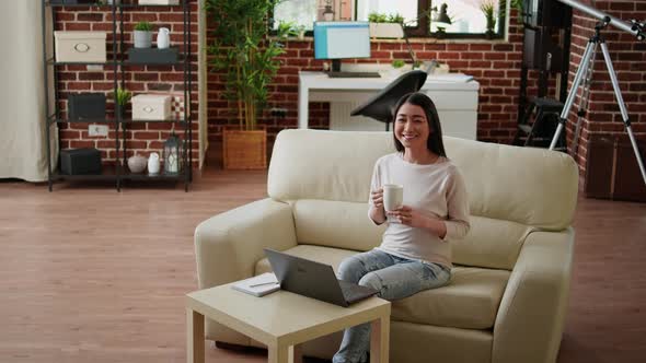 Beautiful Student Sitting on Couch Inside Modern and Cozy Apartment