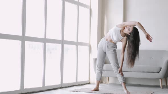 Young Fit Sporty Brunette Girl with Pigtail Does Exercises on Mat in Bright Room