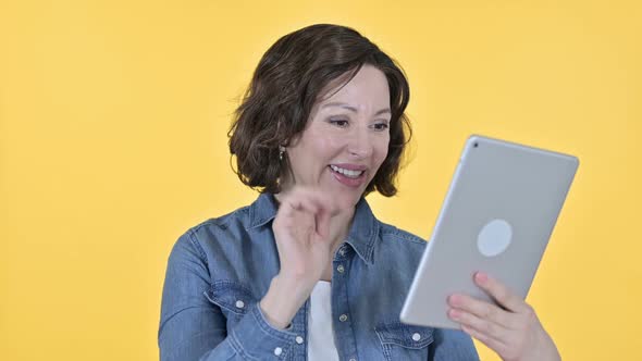 Video Chat on Tablet By Old Woman Yellow Background