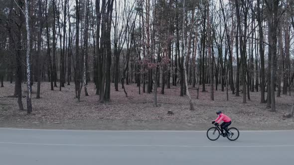 Professional woman cyclist is riding and training on road bike alone. Woman cycling on road bike