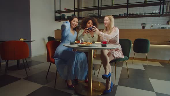 Joyful Multiracial Females Having Fun Dancing at Cafe Table