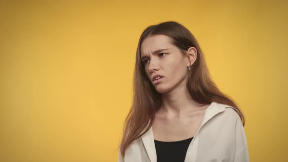 Young Adult Caucasian Woman is Upset on a Bright Yellow Background