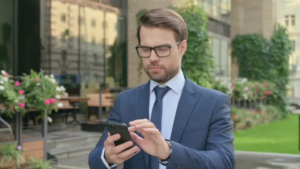 Businessman using Smartphone while Walking in Street in Slow Motion