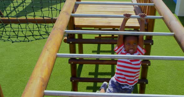 High angle view of African American schoolboy playing on horizontal ladder in school playground 4k