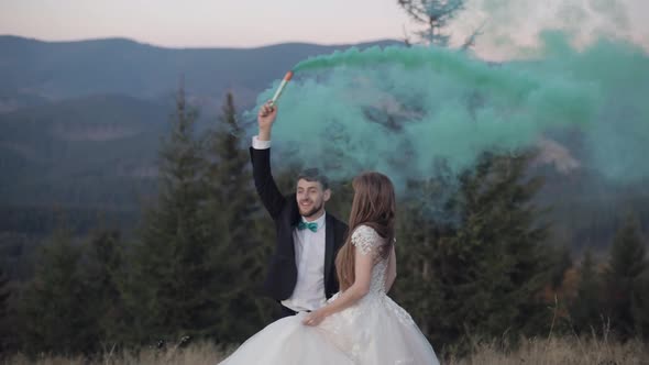 Newlyweds. Caucasian Groom with Bride on Mountain Slope with Smoke Bomb