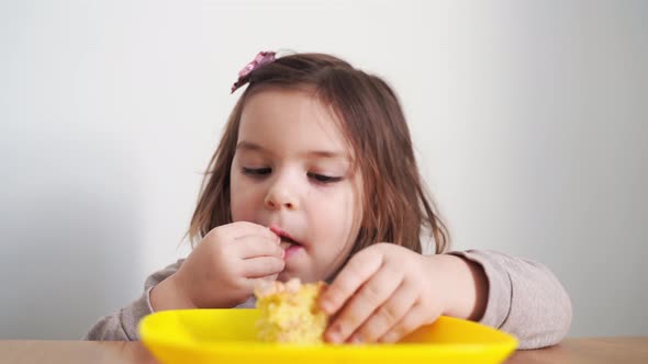 Toddler Girl Eating Bread or Pie at Home with Her Hands