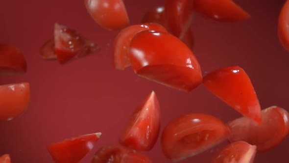 Slices of the Ripe Juicy Tomato are Bouncing and Rotating on the Red Background
