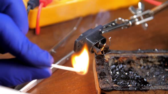 Person in Blue Gloves Burns Match at Black Socket Closeup
