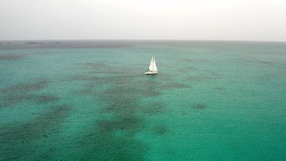 Aerial View of Sailboat in Open Tropical Sea Sailing To Horizon, Drone Shot
