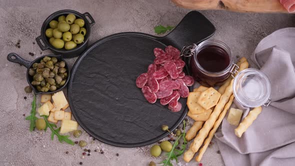 Woman Puts Slices of Fuet Sausage Onto Stone Serving Board at Domestic Kitchen