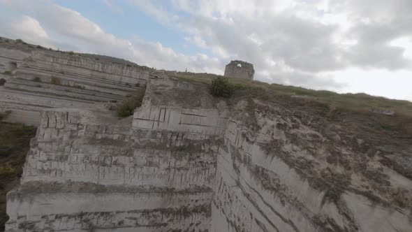 Drone Freestyle Flying Along Flat White Cliff Edge and Ancient Fortress