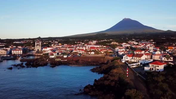 Aerial landscape shot of Madalena town and the coast in Pico Island at sunset. Mount Pico in the bac